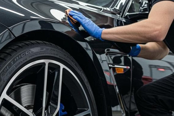 Man Cleaning and Detailing Black BMW Sedan